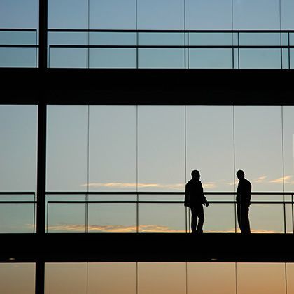 silhouettes of two men standing and watching sunset