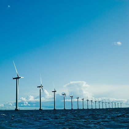 row of windmills standing in the sea against blue sky
