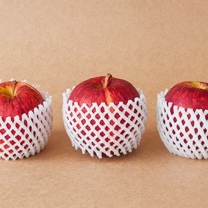 group of red apples with protective packaging on paper background